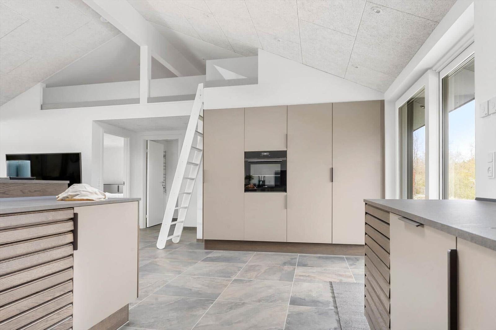 Moderne Küche mit Hochbett und integriertem Ofen. Große Fenster und helles Design.