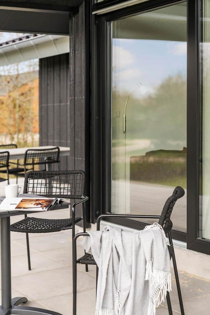Terrasse mit Tisch, Stühlen und Decke. Große Glastür führt ins Haus.