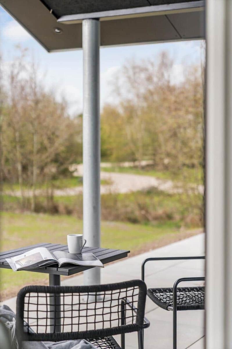 Terrasse mit Tisch, Stühlen und Blick auf Grünflächen.