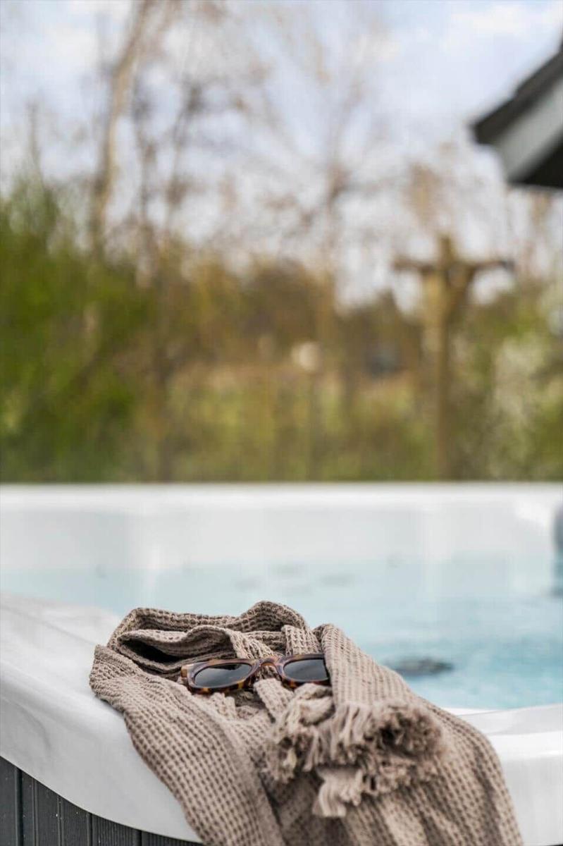 Eine Brille liegt auf einem Handtuch am Rand einer Whirlpool-Badewanne.