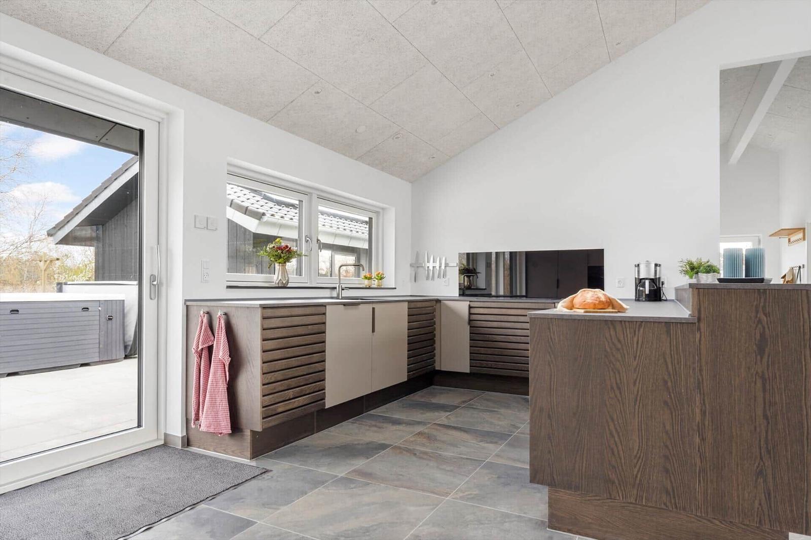 Moderne Küche mit Holzschränken, Arbeitsfläche und Blick auf Terrasse mit Whirlpool.