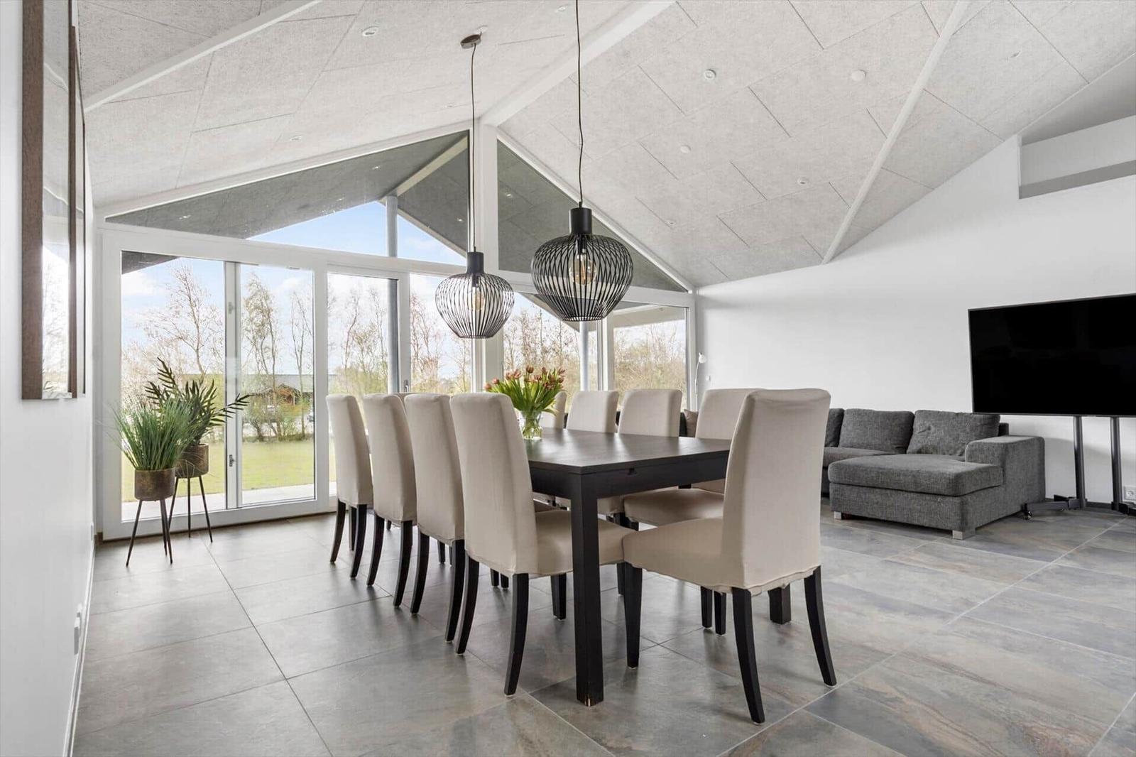 Essbereich mit Tisch und Stühlen, Wohnbereich mit Sofa und Fernseher, große Fensterfront
