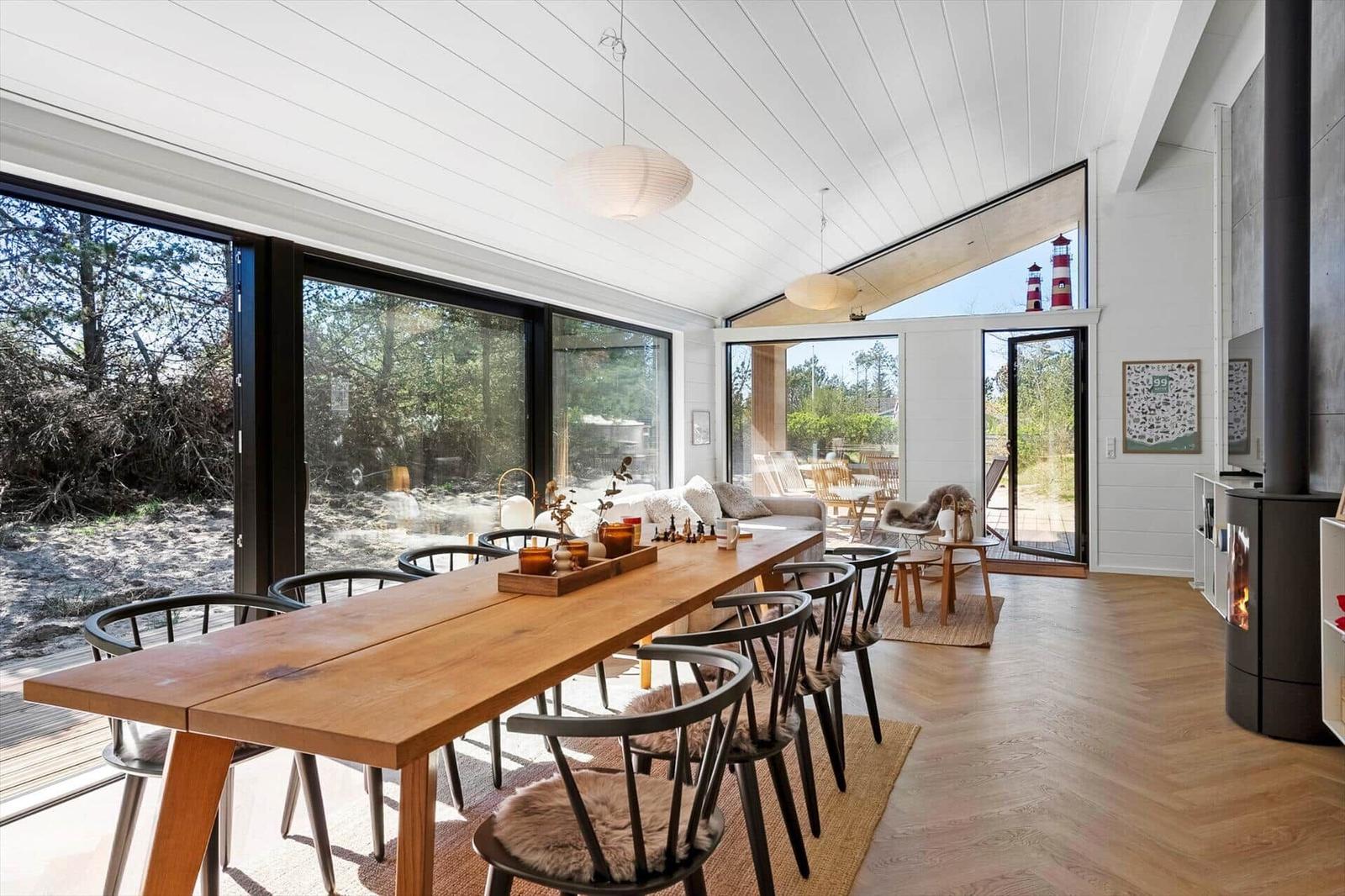 Dining room with wooden table, chairs, and view of nature.