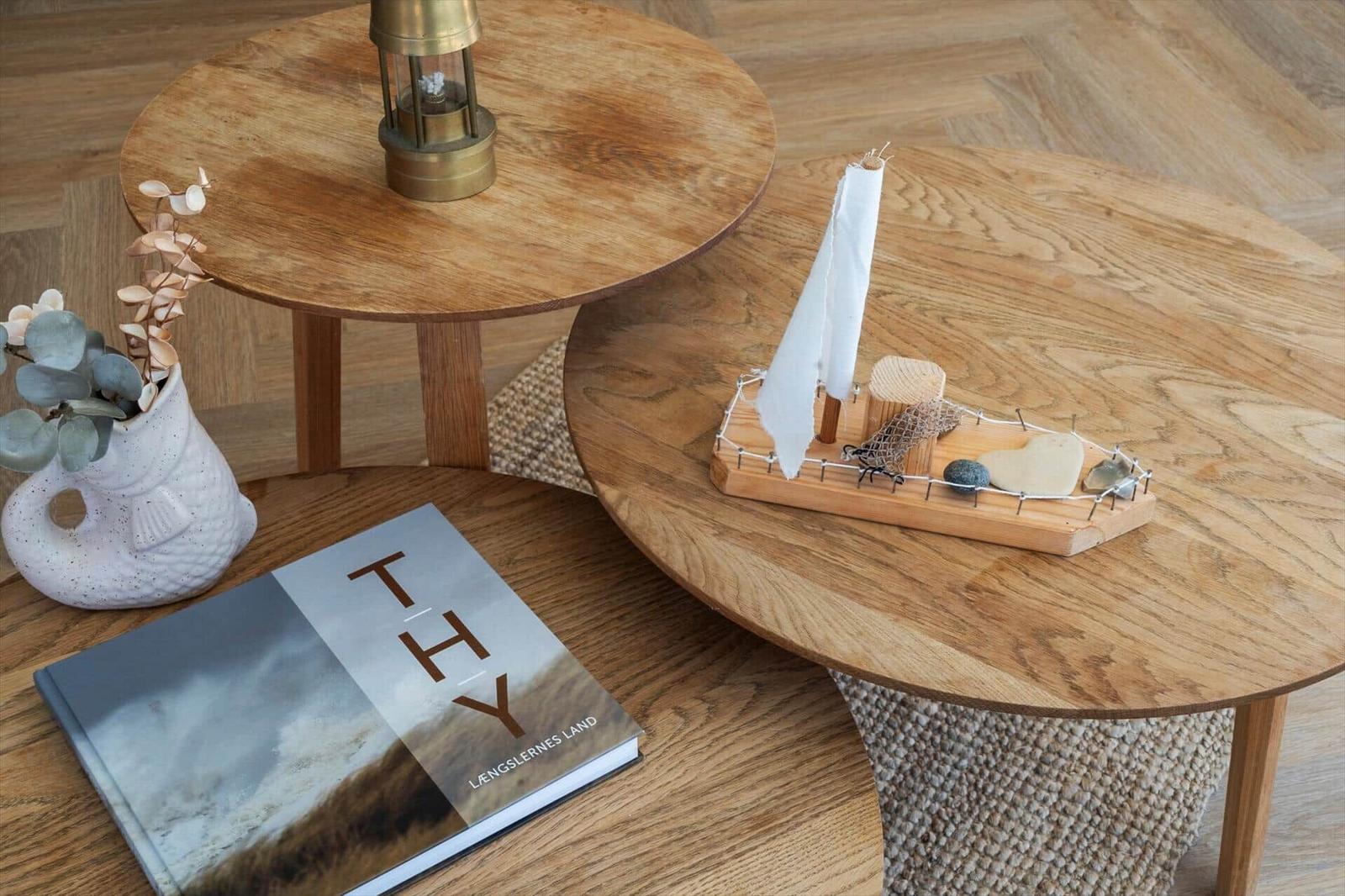 Wooden table with sailboat, book, and vase on wooden floor