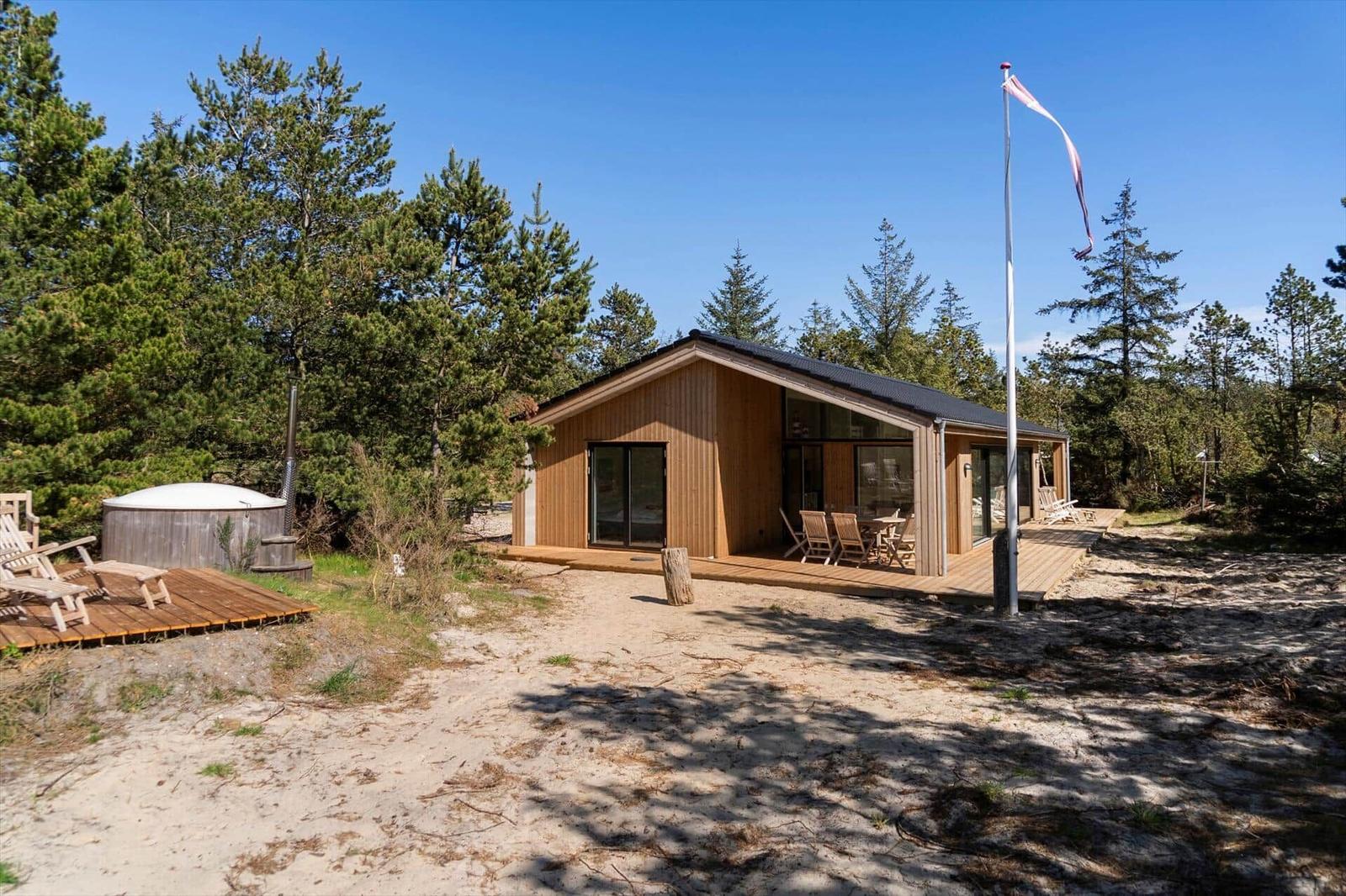 Wooden cabin with terrace, garden furniture, and hot tub in the woods.