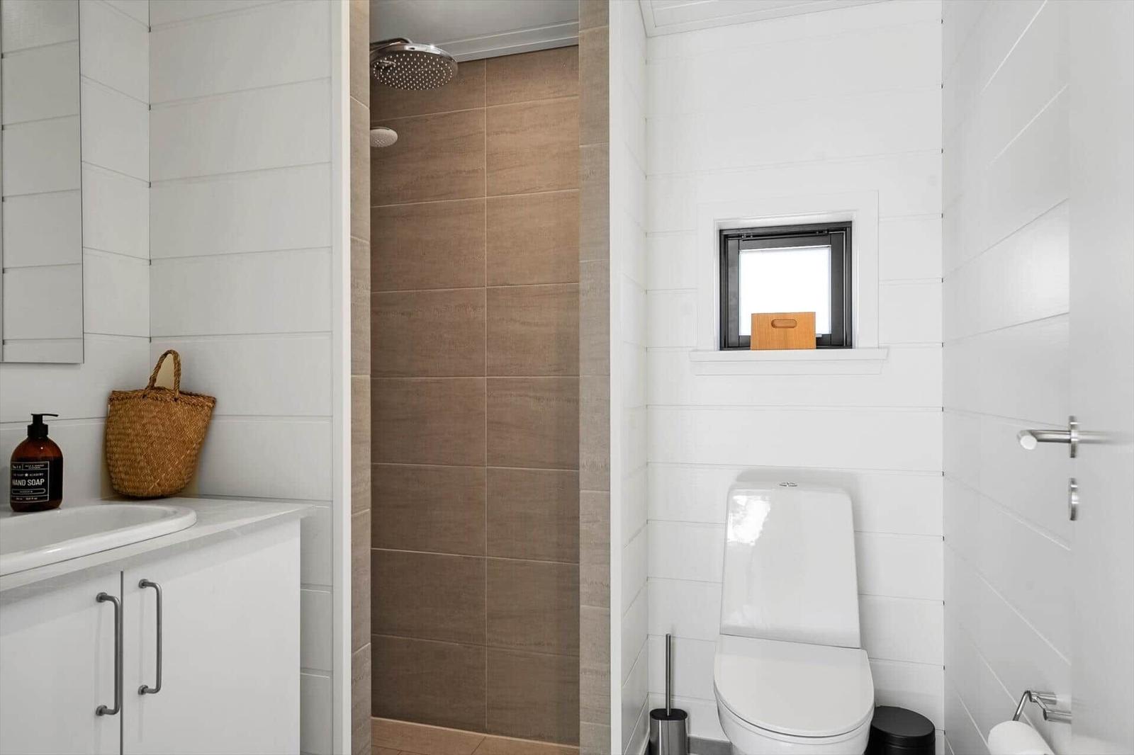Bathroom with shower, toilet, and sink with mirror.