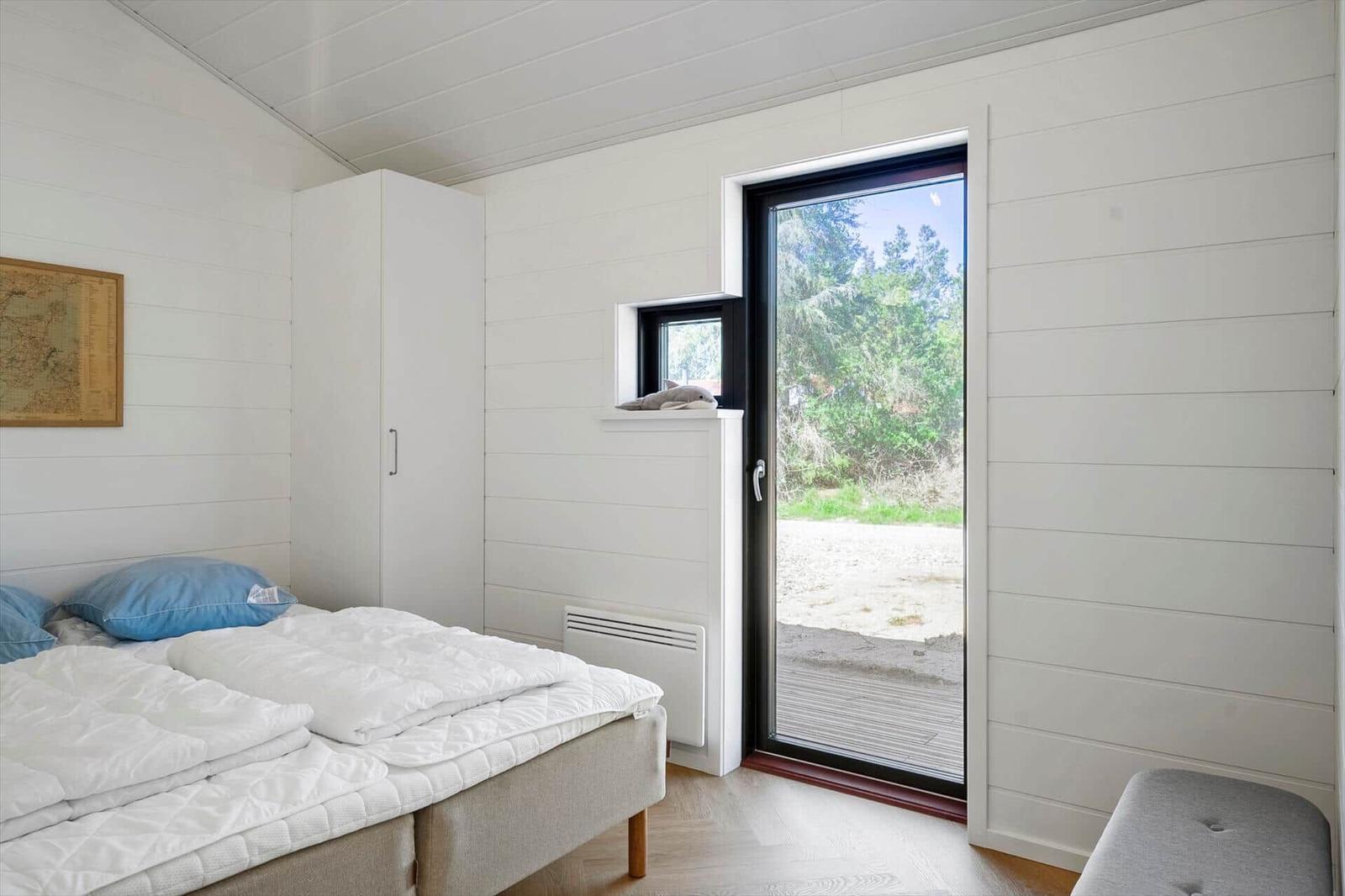 Bedroom with bed, wardrobe, and door to outdoor area.