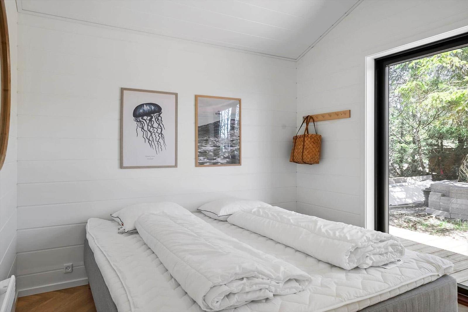 Bedroom with bed, wall art, and window to outside.