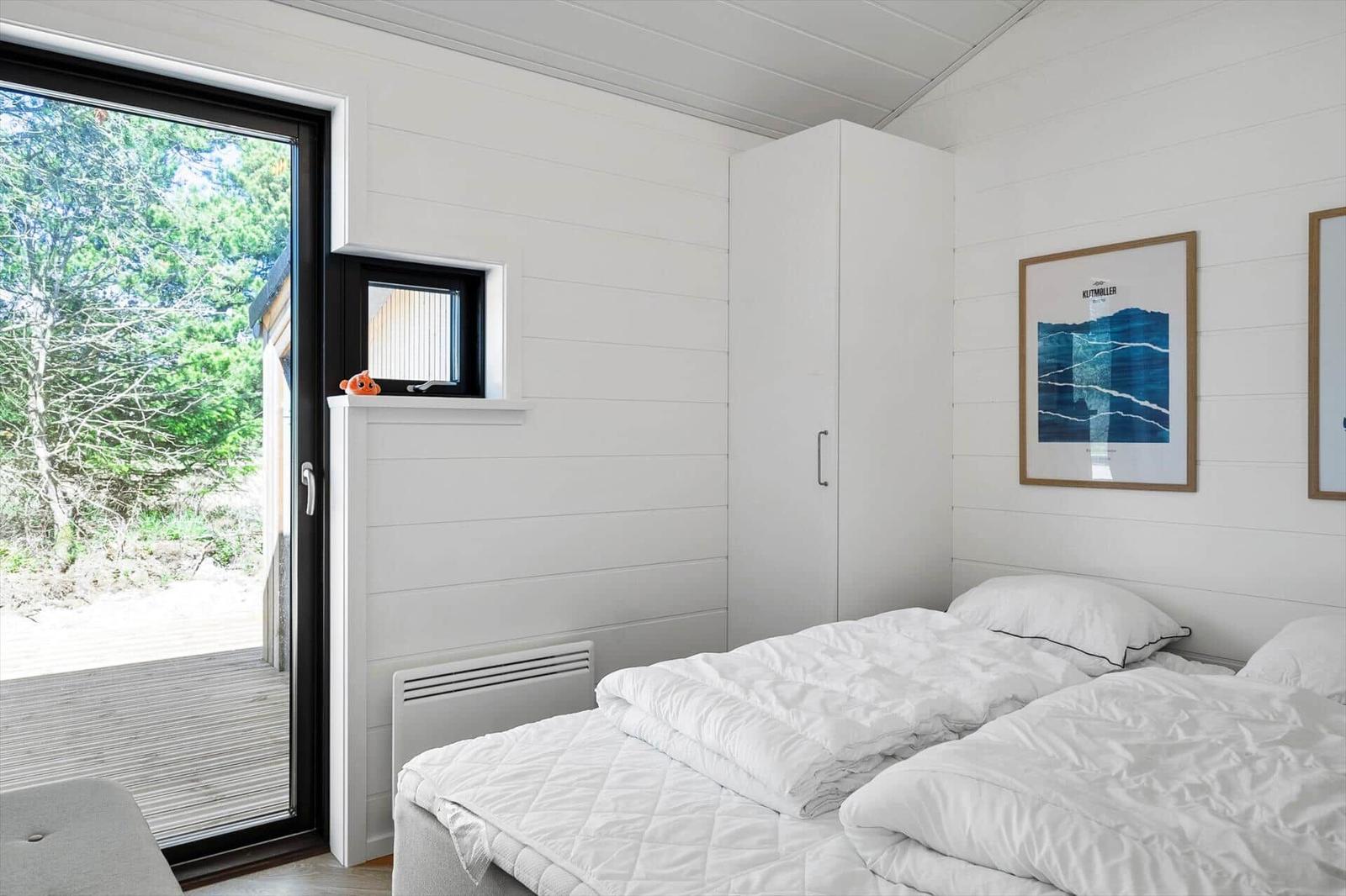 Bedroom with double bed, white walls, and view of outdoor terrace.