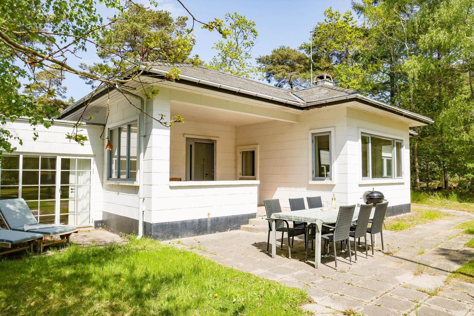 Wohnhaus mit Terrasse, Garten und Grillplatz. Umgeben von Bäumen.