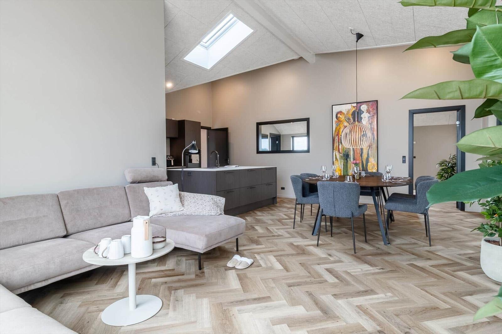 Wohn- und Essbereich mit Sofa, Esstisch und Küchenzeile. Holzboden und Dachfenster.