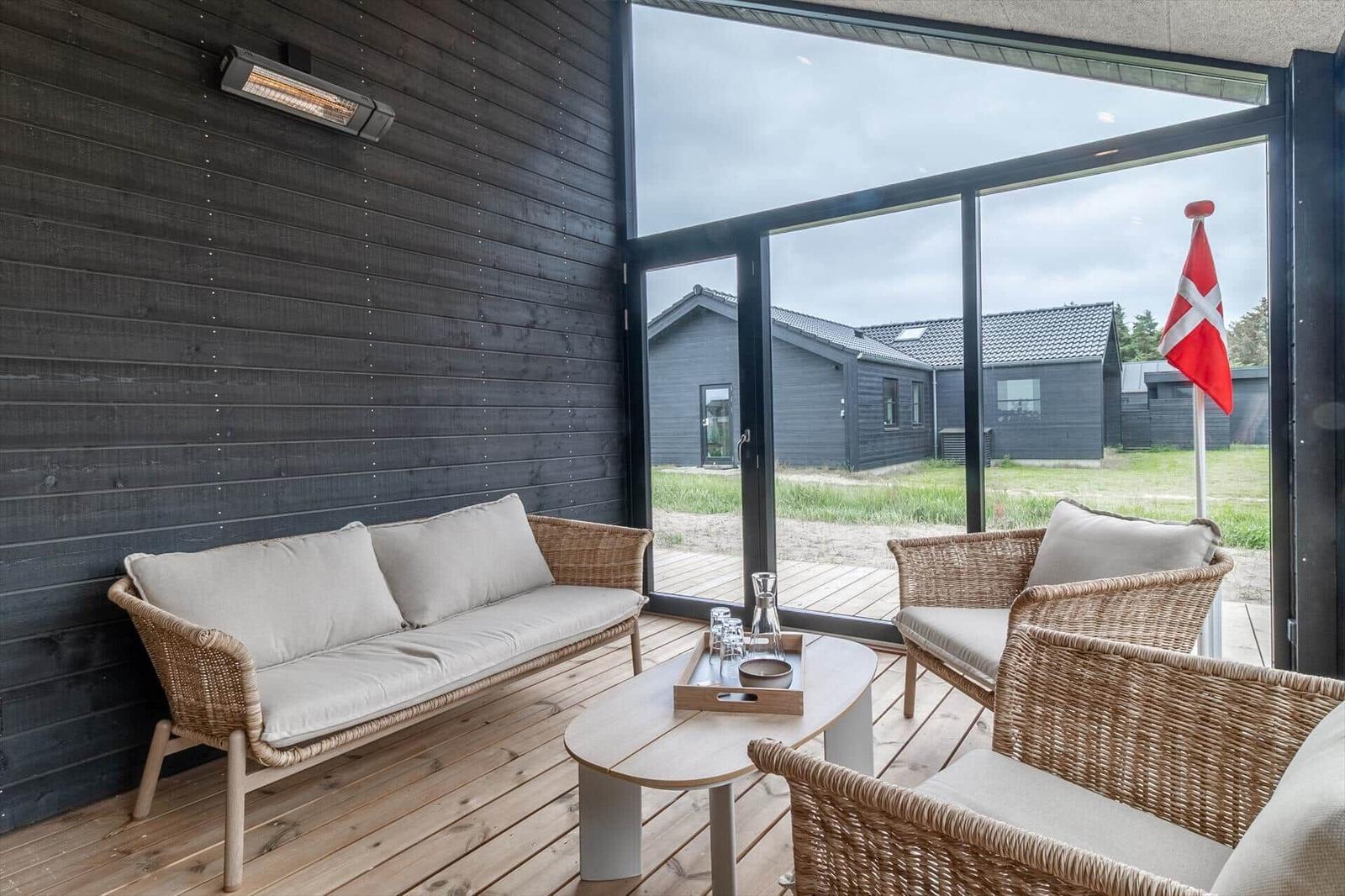 Terrasse mit Sitzgruppe, Holzboden und großem Fenster zur Aussicht