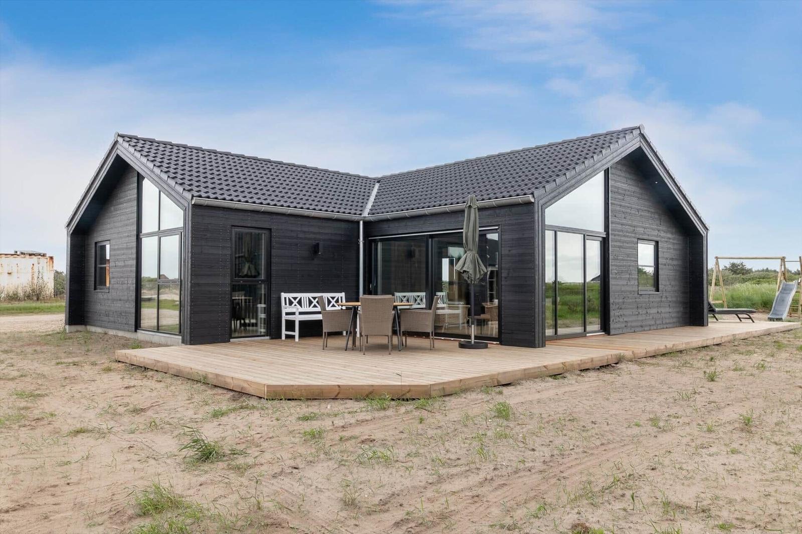 Moderne Strandhaus mit Terrasse, Gartenmöbel und Schiebetüren zur Außenterrasse.