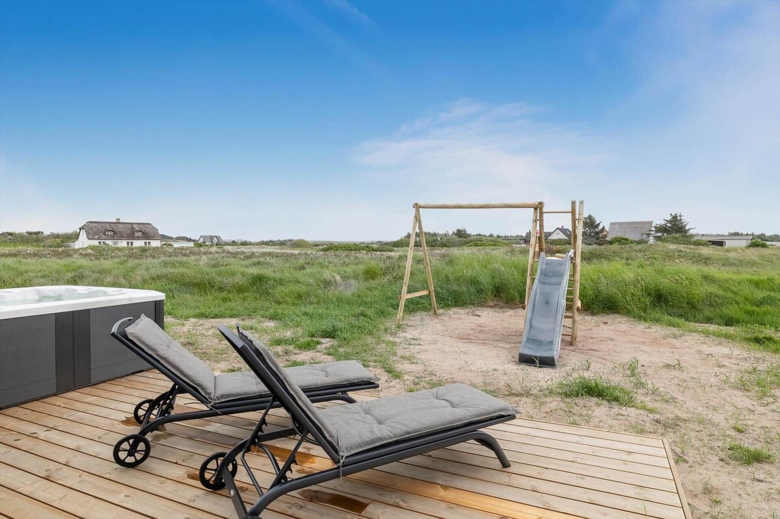 Terrasse mit Liegestühlen, Whirlpool und Kinderspielplatz im Freien.