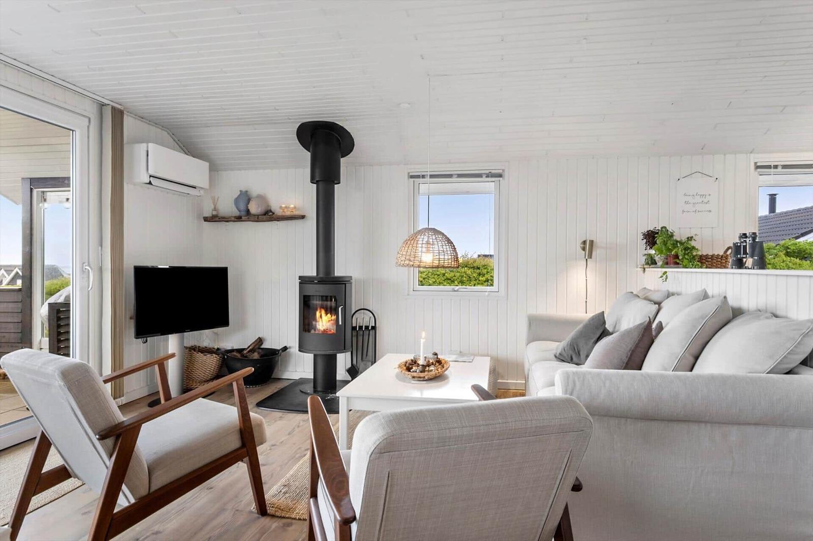 Living room with fireplace, sofa, and TV. Wooden floor and white walls.