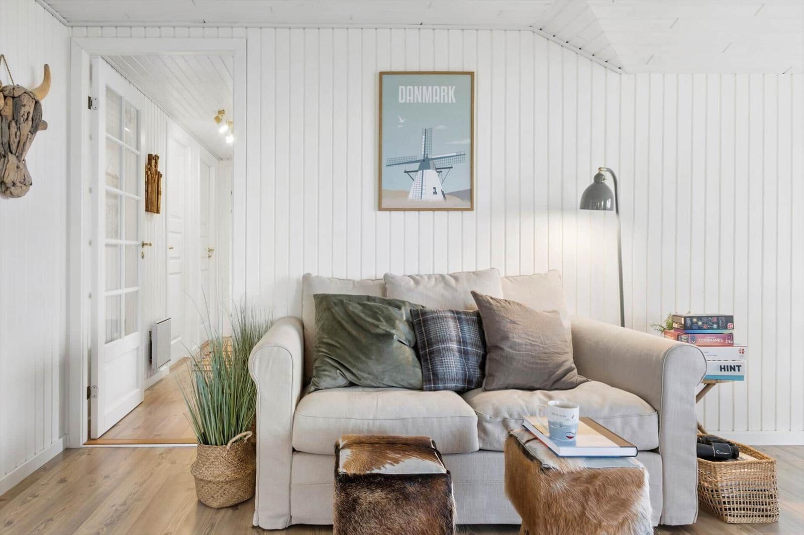 A living room with a sofa, cushions, and a picture on the wall.