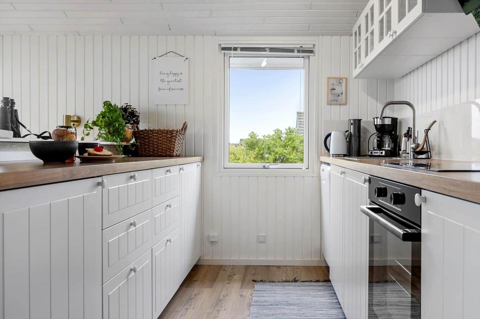 Kitchen with white cabinets, wooden countertops, and window view of trees.