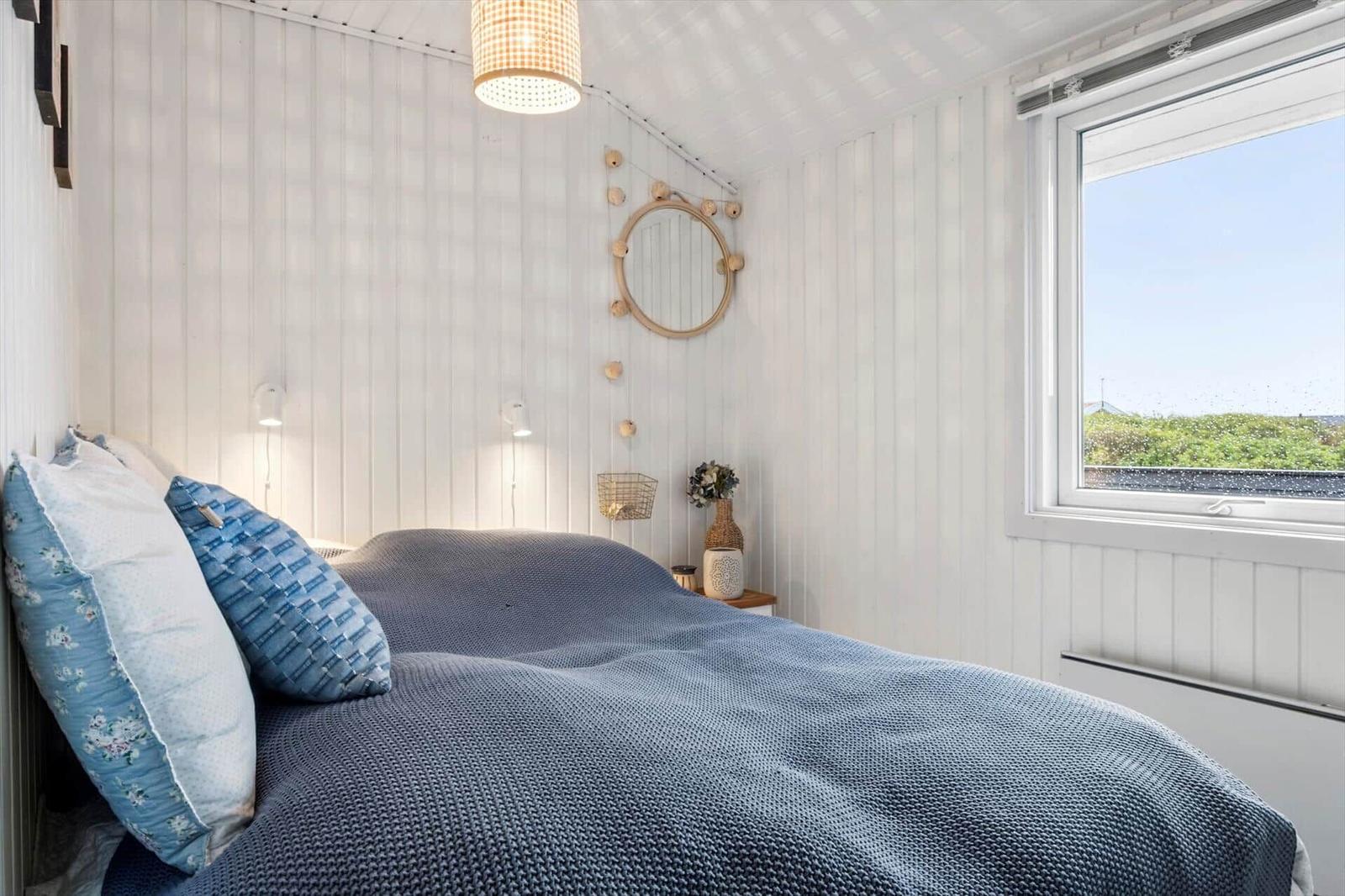 Bedroom with bed, window, and wall mirror