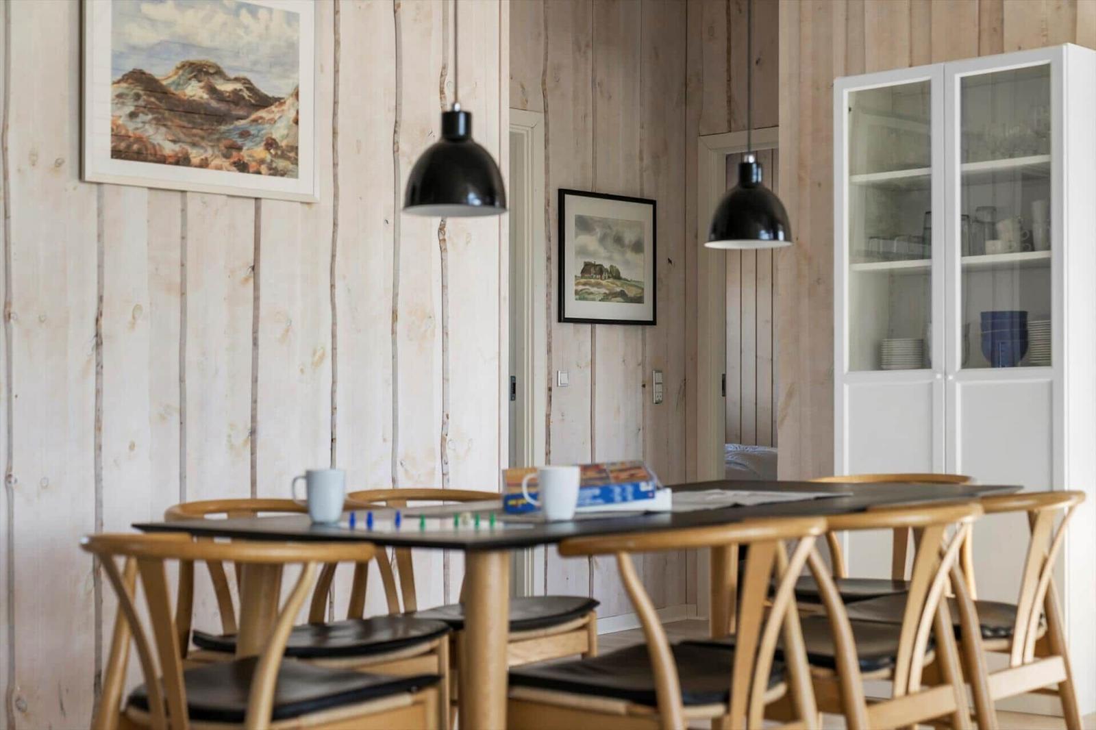 Esszimmer mit Holzwand, Tisch, Stühle und Glasvitrine.