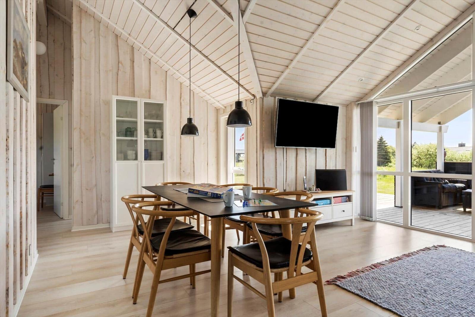 Essbereich mit Holztisch, Stühlen und Fernseher an der Wand.