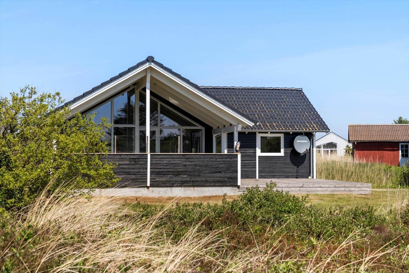 Moderne Villa mit großem Glasbereich und Holzterrasse im Freien.