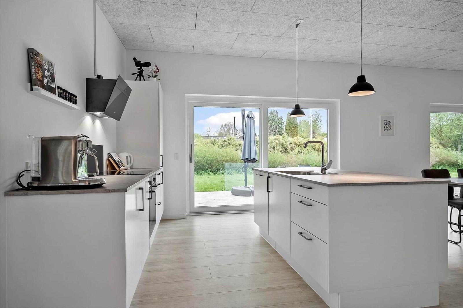 Moderne Küche mit Insel, Blick auf Garten und Terrasse.