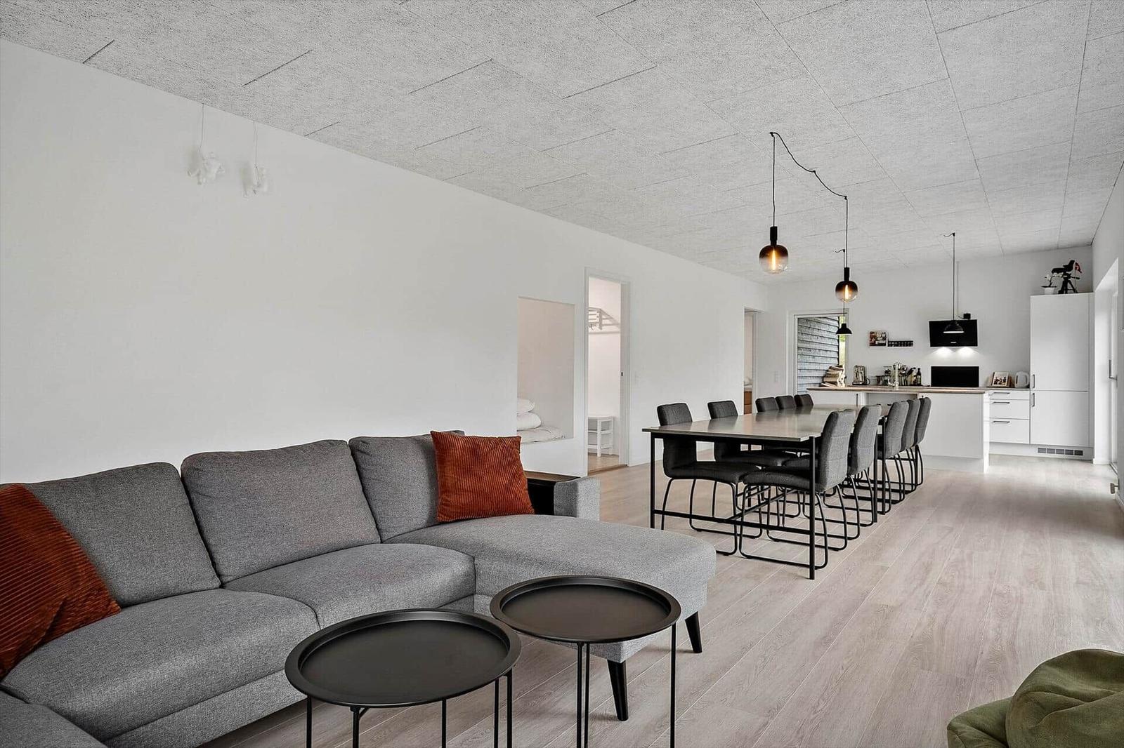 Wohnzimmer mit grauem Sofa, Essbereich und Küche im Hintergrund.