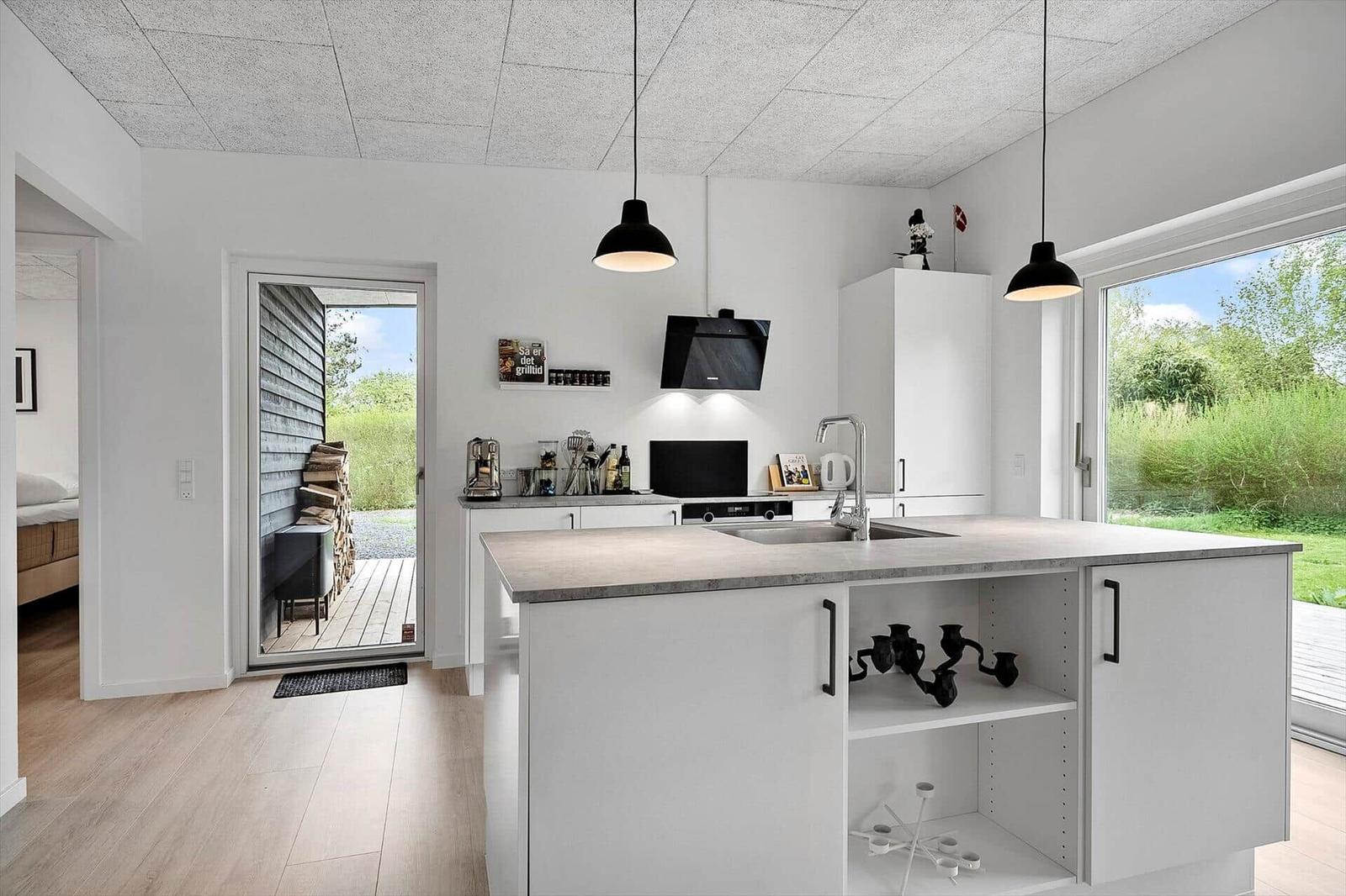 Moderne Küche mit Kücheninsel, weißen Schränken und Blick auf Garten.