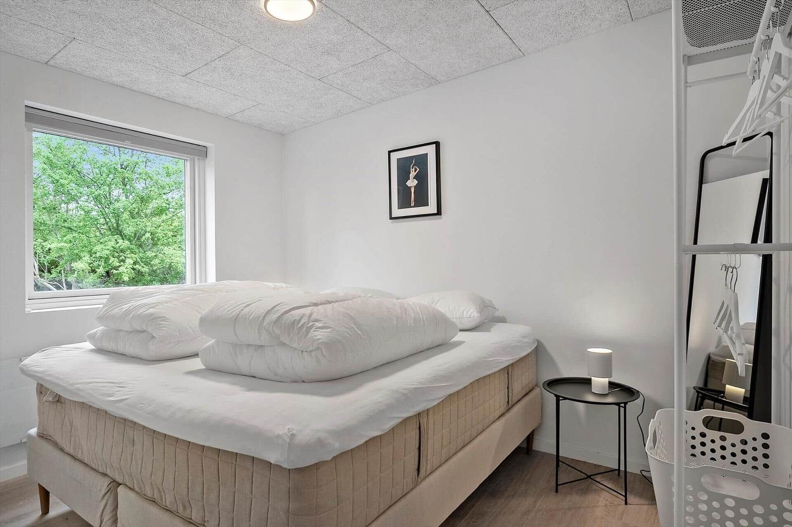 Schlafzimmer mit Bett, Fenster und Kleiderständer