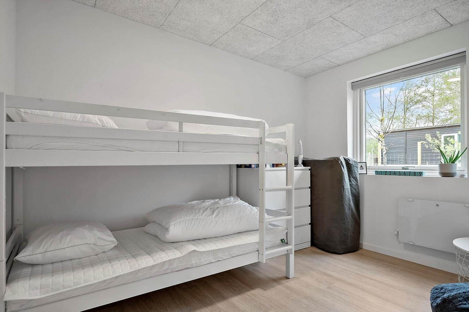Zimmer mit Doppelstockbett, Fenster und Schrank.