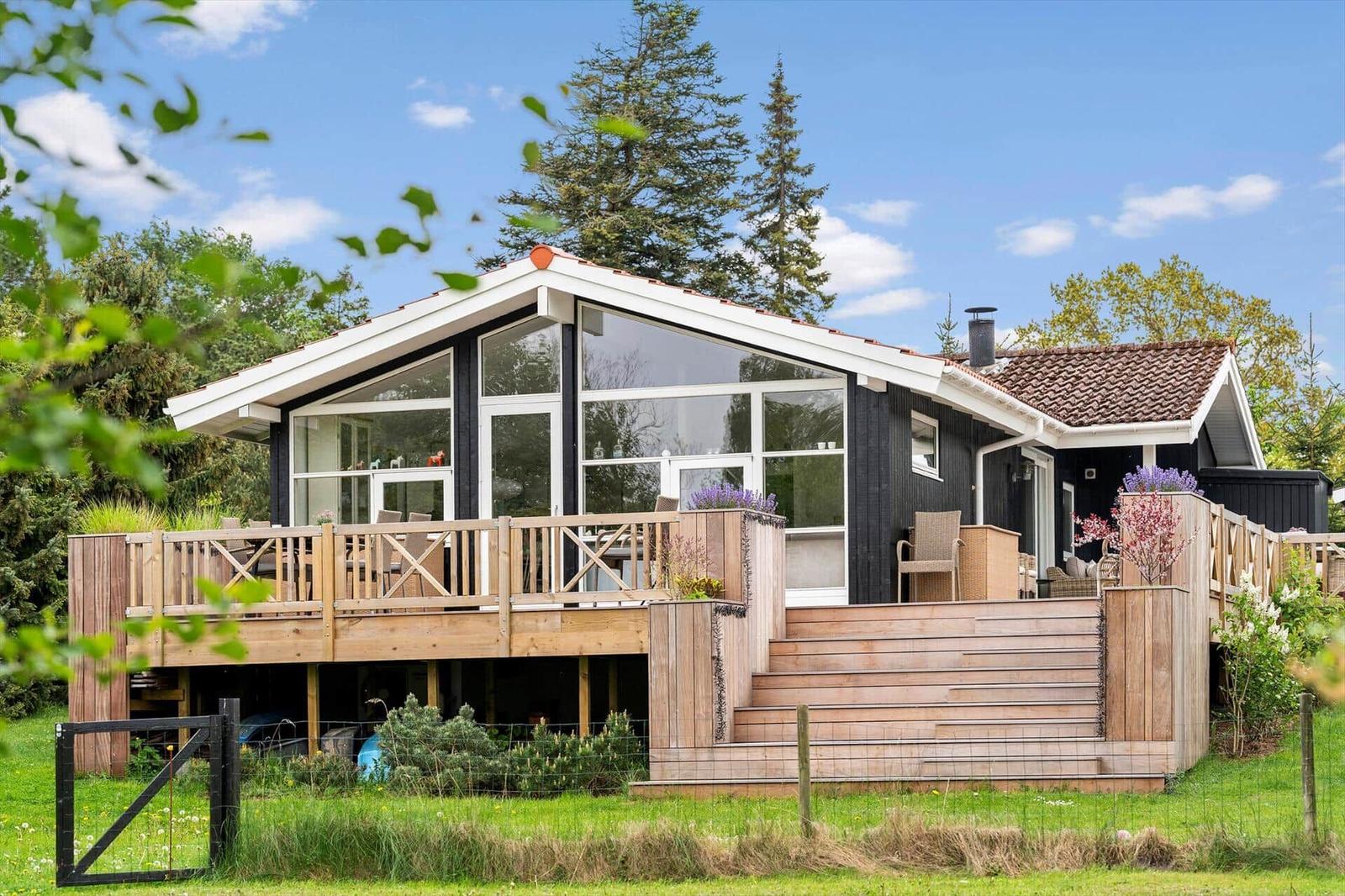 Moderne Holzhütte mit großem Balkon und Terrasse im Grünen.