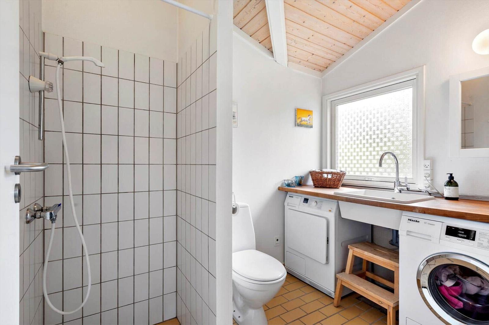 Badezimmer mit Dusche, Toilette, Waschmaschine und Wäschetrockner.