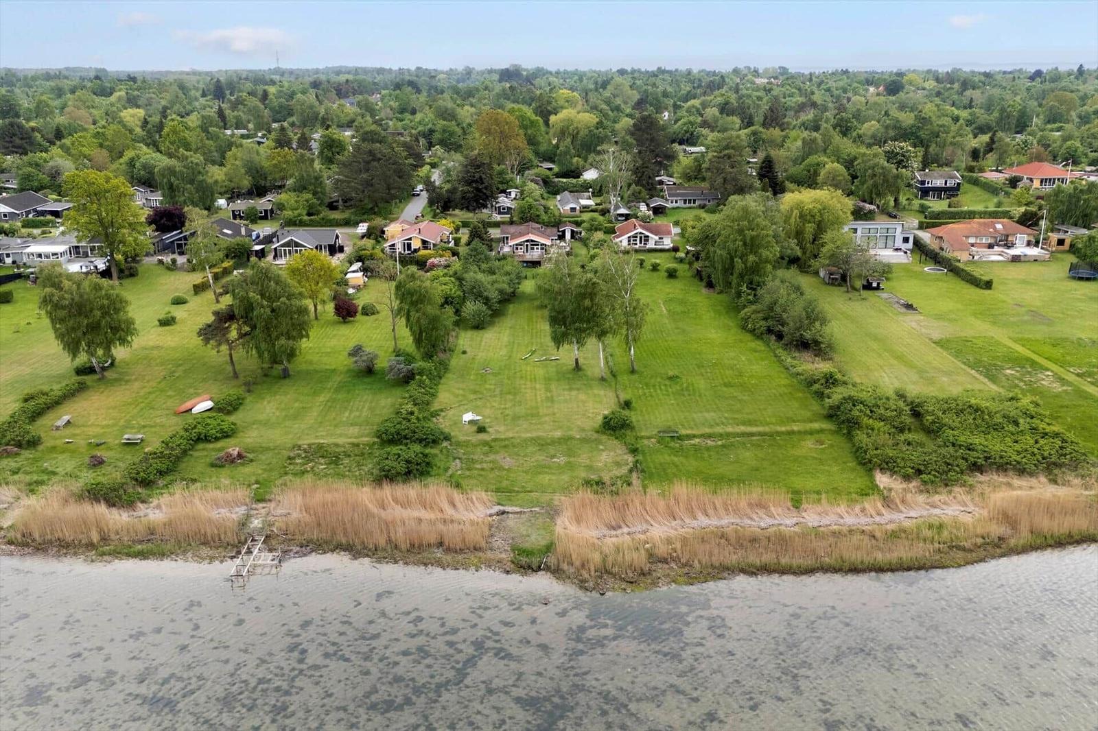 Grüner Garten mit Blick auf Wasser und Wohnhäuser im Hintergrund.