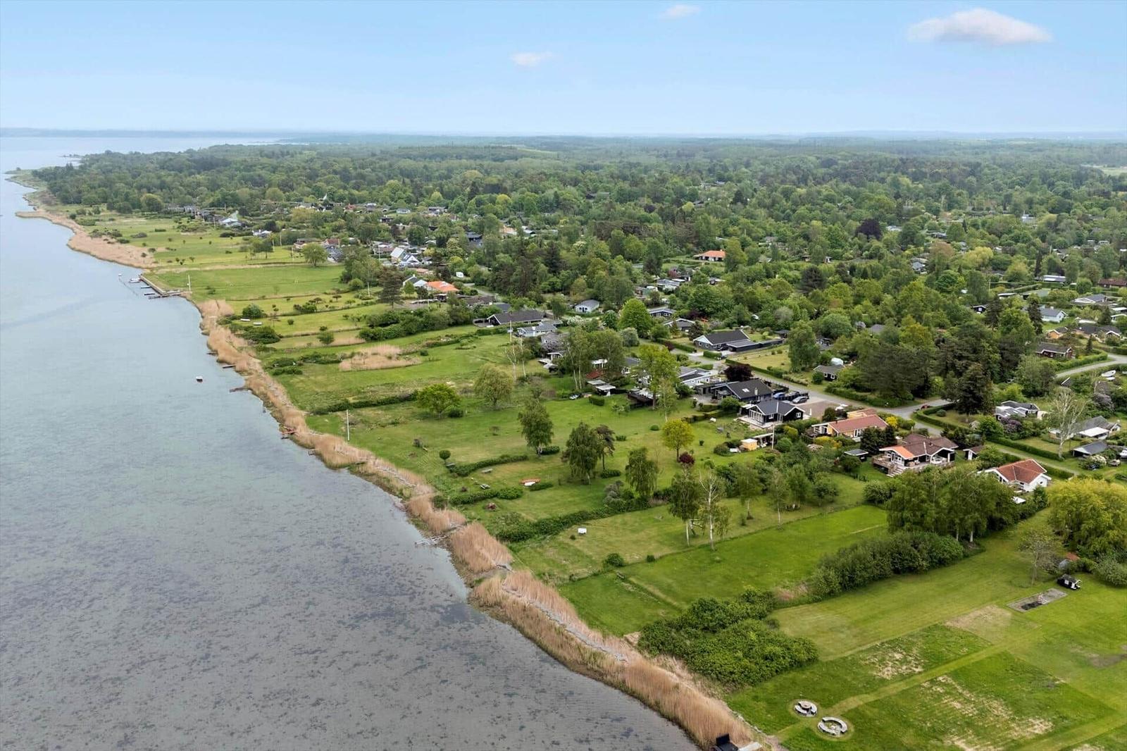 Luftbild einer Küstenlandschaft mit Häusern und Grünflächen entlang des Wassers.