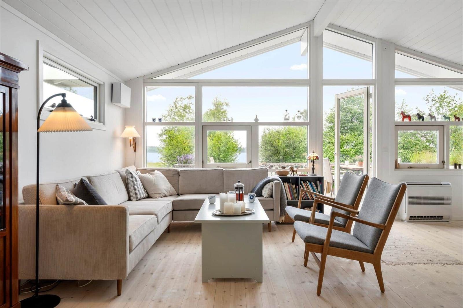 Wohnzimmer mit Sofa, Stühlen und großem Fensterblick auf Grünflächen.