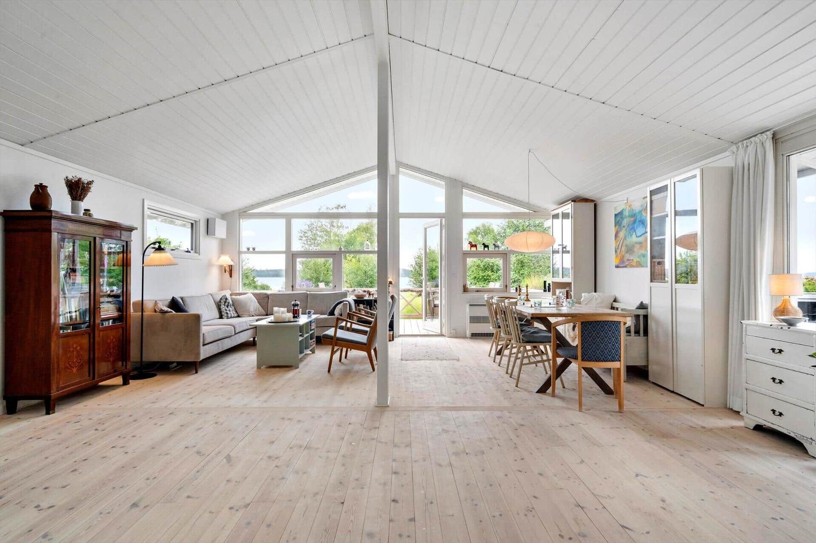 Großes Wohn- und Esszimmer mit Holzboden, großen Fenstern und moderner Einrichtung.