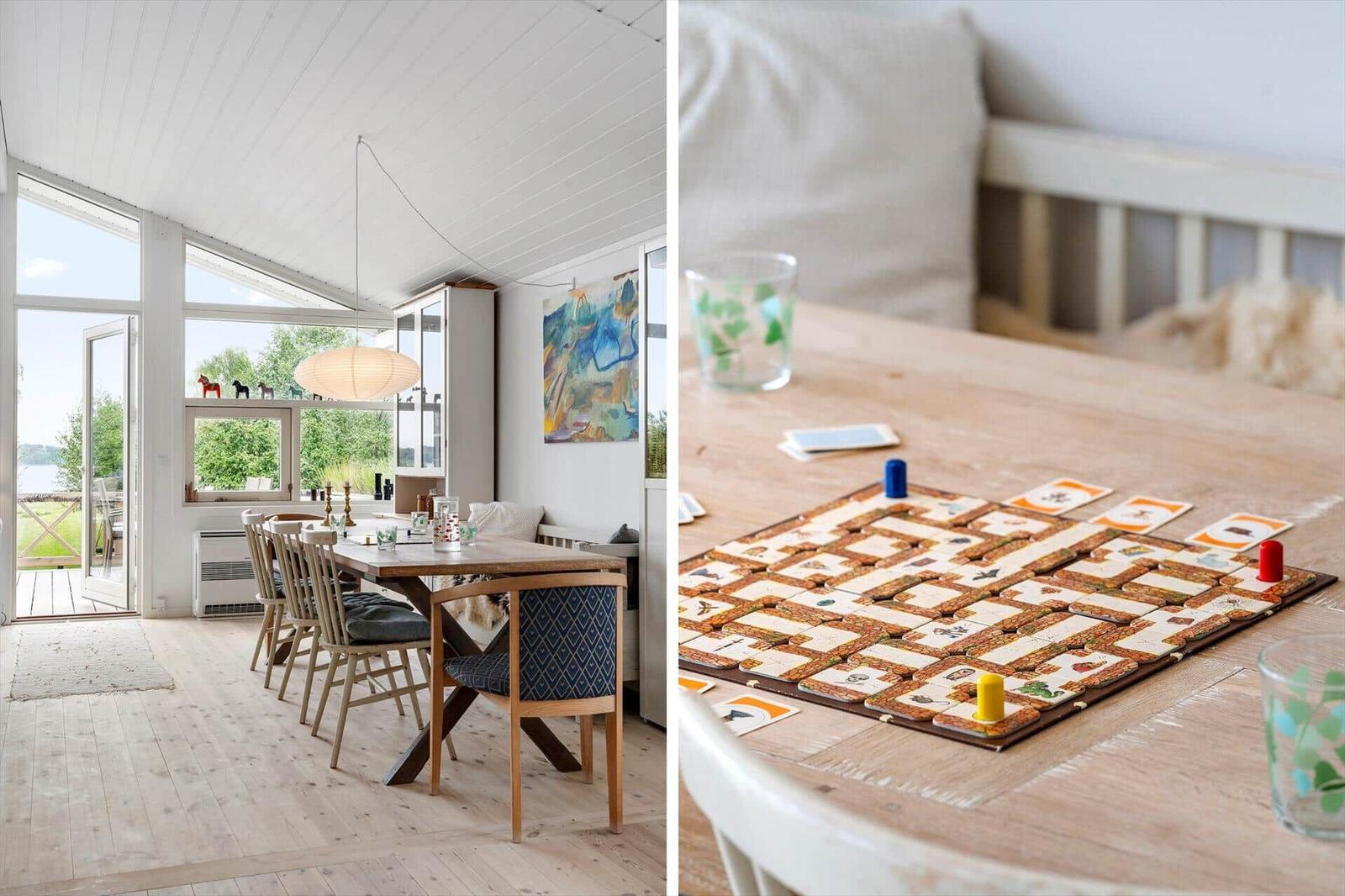 Essbereich mit Tisch und Stühlen, große Fenster, Spiel auf Holztisch.