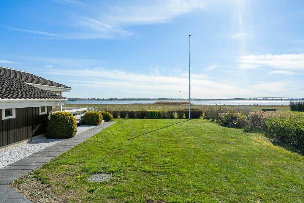 House with garden, view of water and bridge under blue sky.