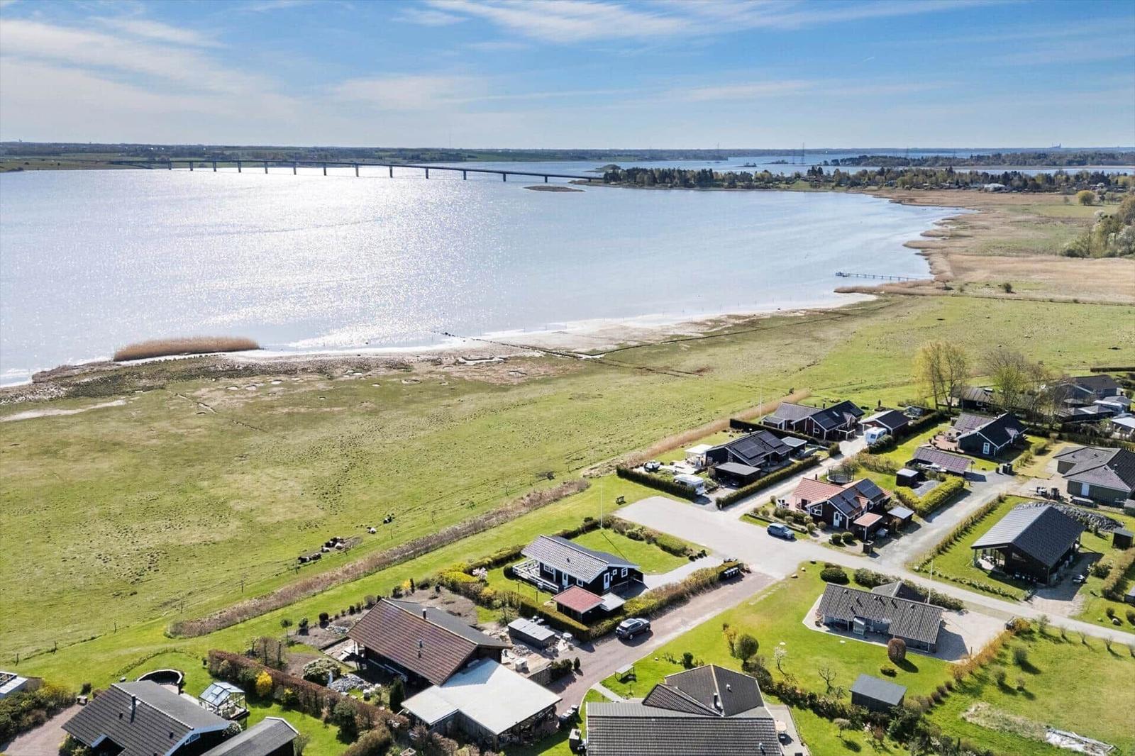 Aerial view of houses by a lake with a bridge in the background.