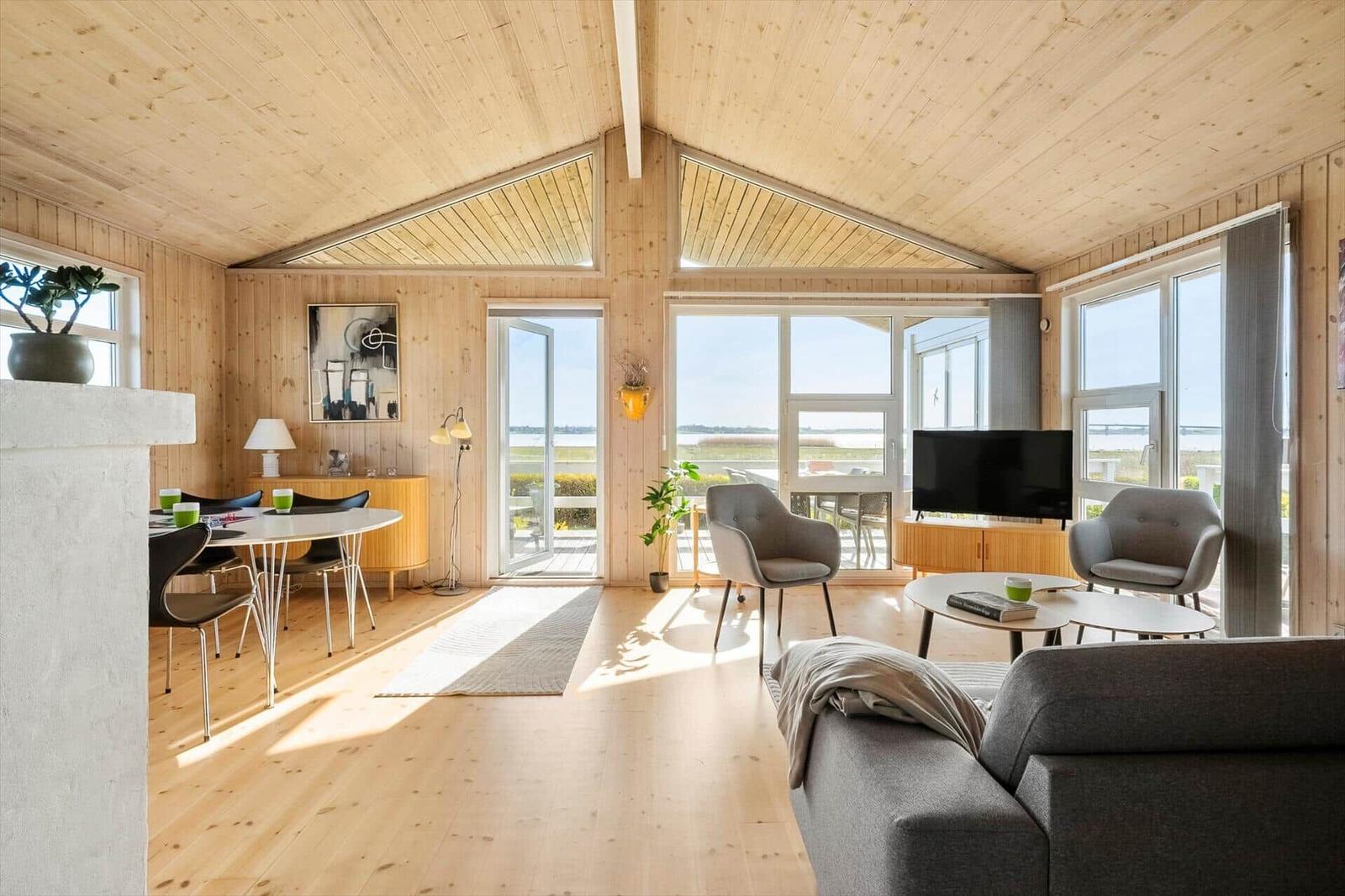 Living and dining area with wooden ceiling, large windows, and view of the landscape.