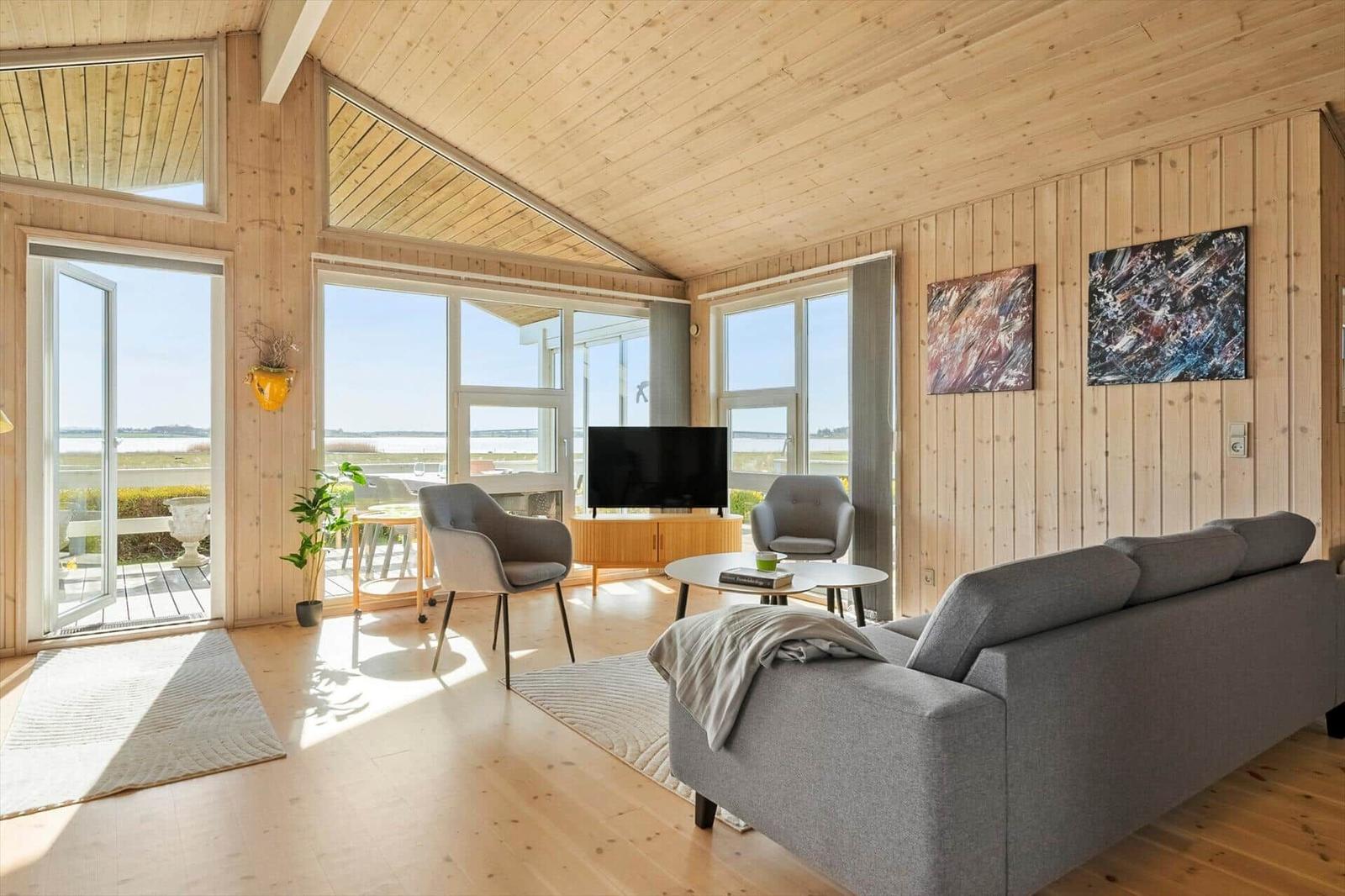 Living room with wooden walls, sofa, TV, and large windows for views.