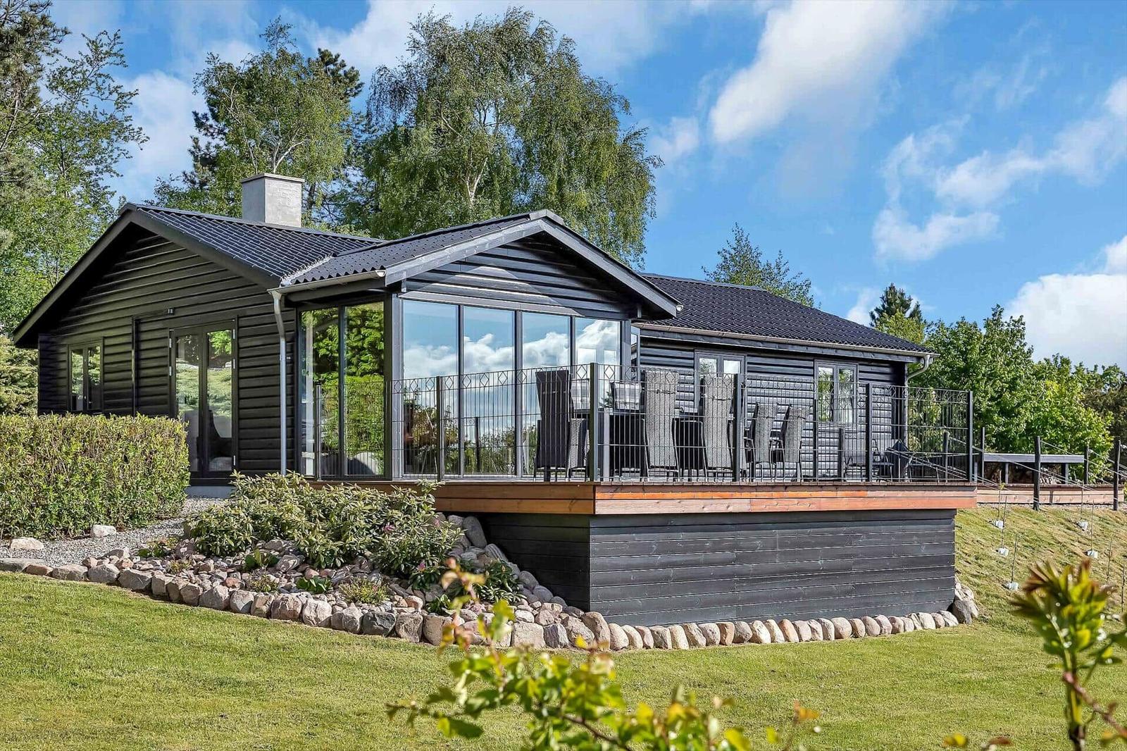 Modern wooden cabin with terrace and large glass area in the green.