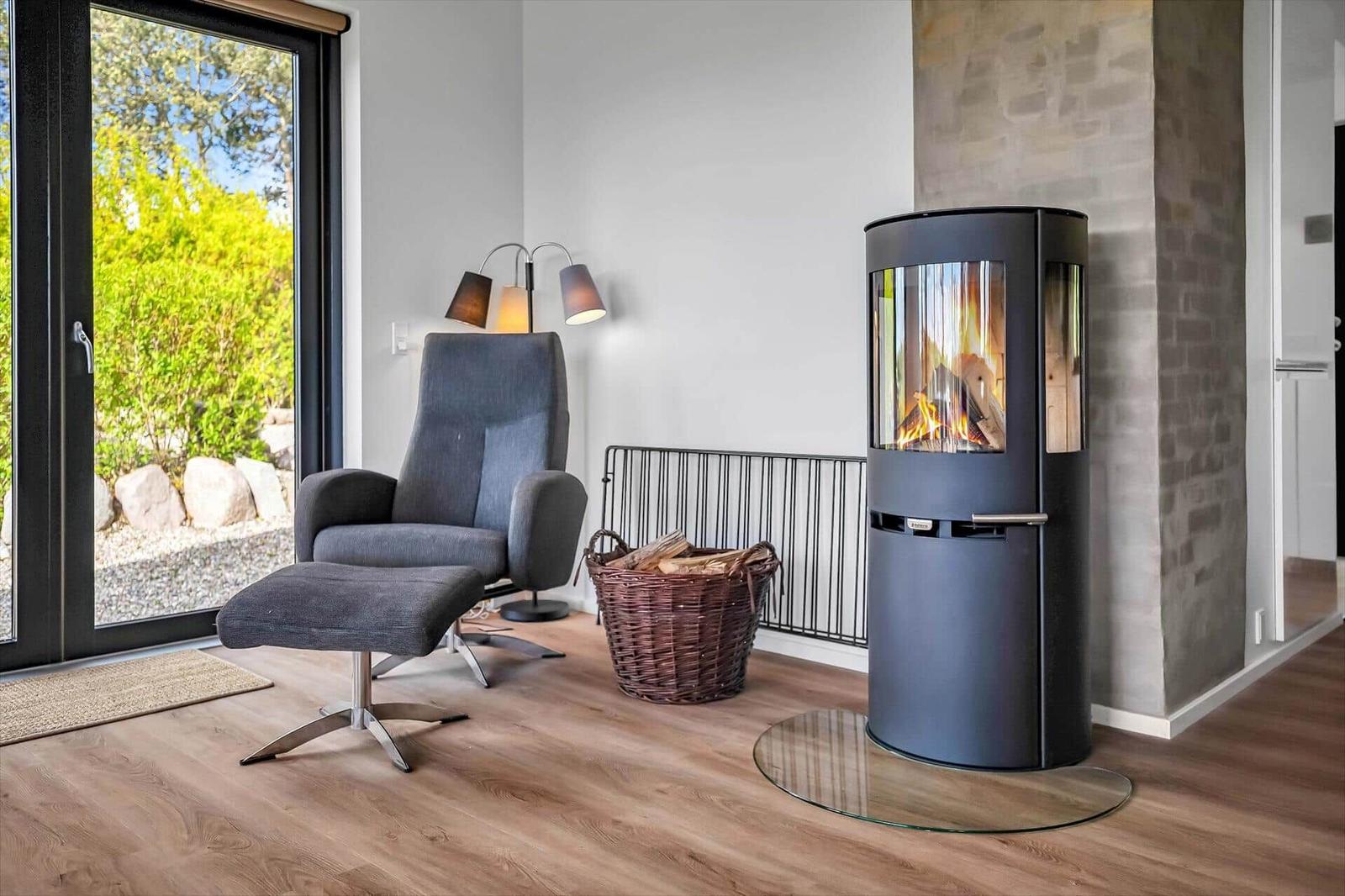 Room with armchair, fireplace, and glass door to outdoor terrace.