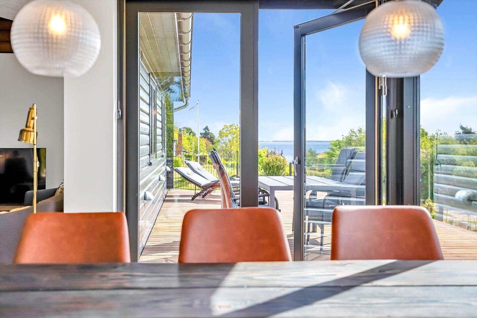 Through the glass doors, you can see a terrace with loungers and a view of the water.
