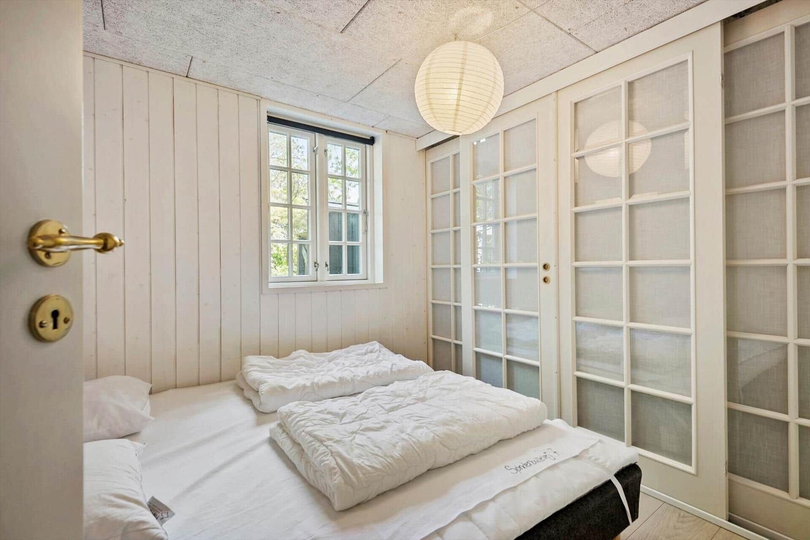 Schlafzimmer mit Bett, Fenster und Glaswand