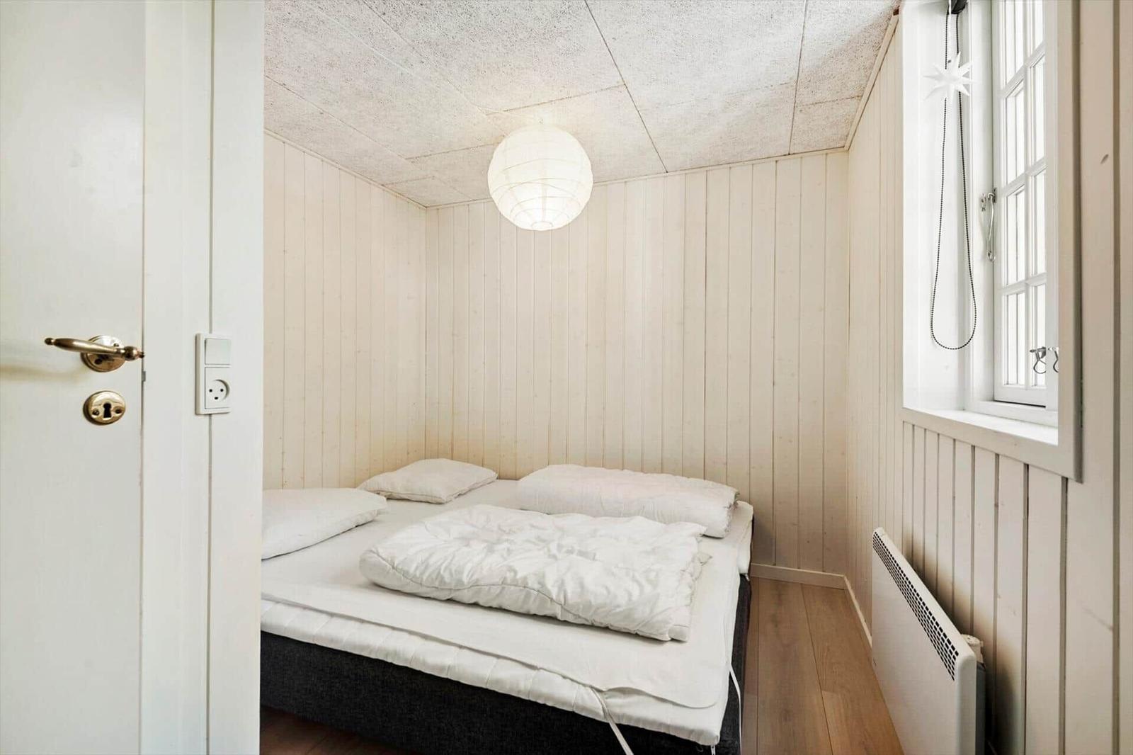 Schlafzimmer mit Bett, Fenster und Deckenleuchte.