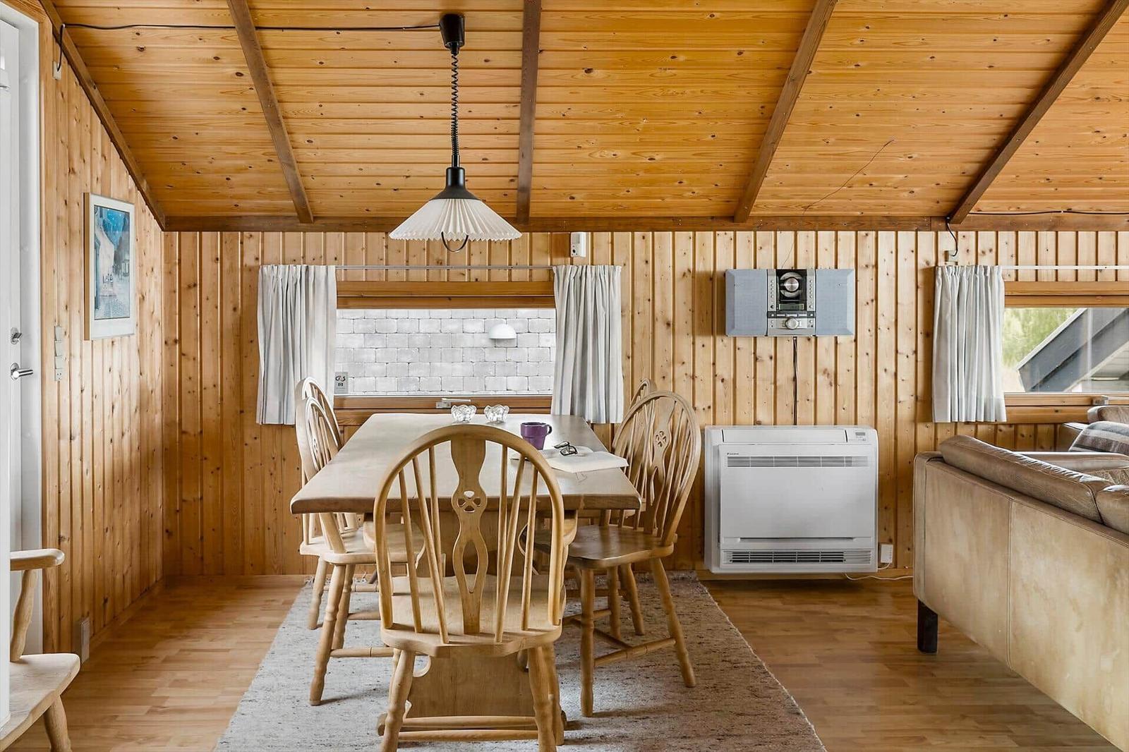 Esszimmer mit Holztisch, Stühlen und Sofa. Holzwände, Decke und Boden.
