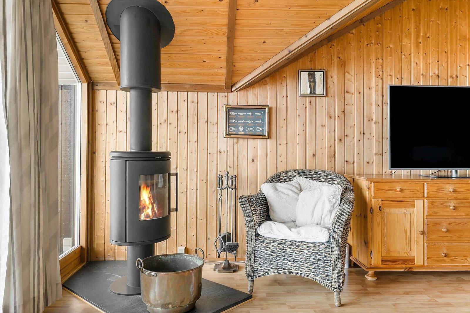 Wohnraum mit Holzwand, Kaminofen, Sessel und Fernseher