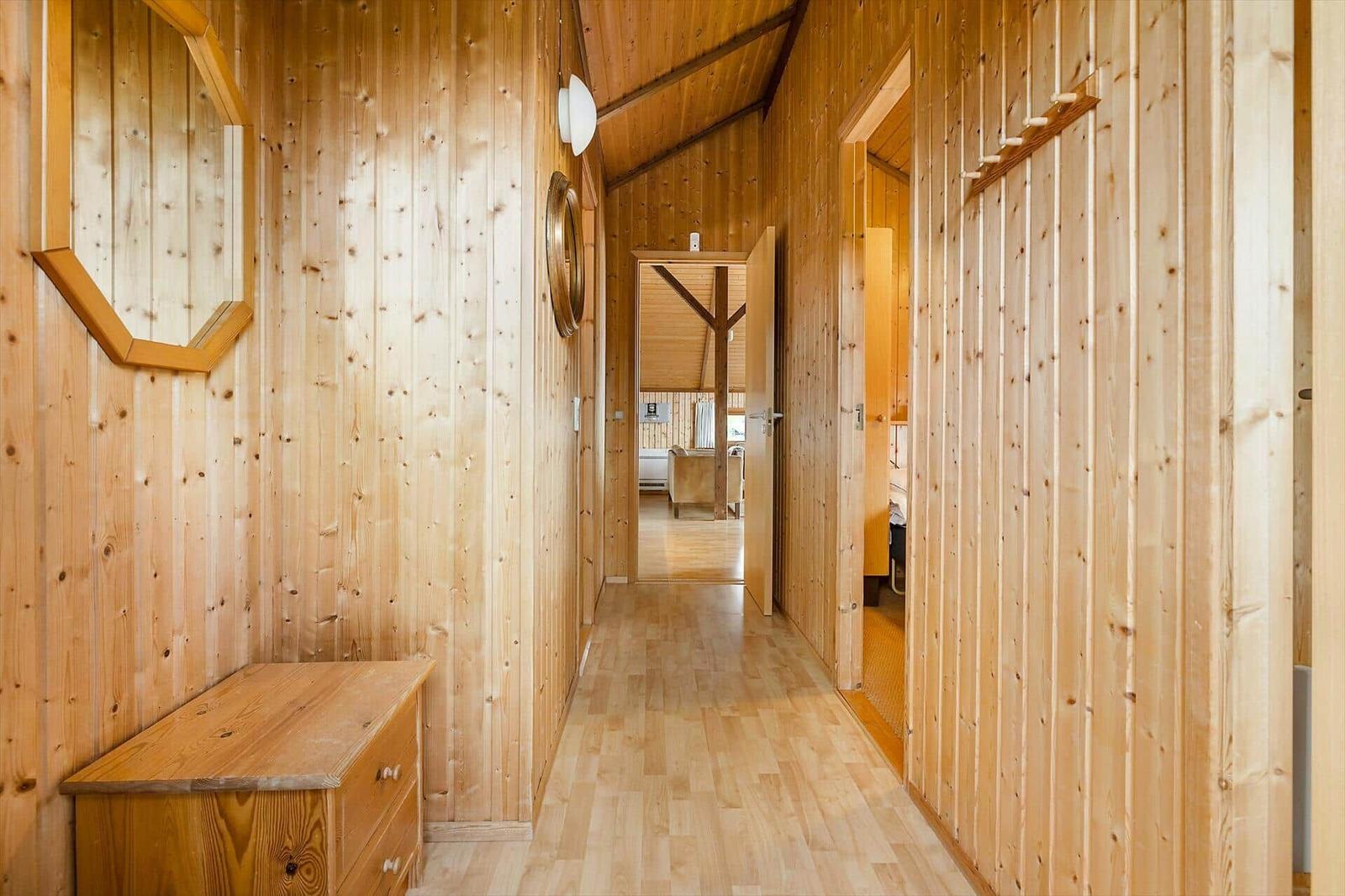 Holzverkleideter Flur mit Schrank, Spiegel und Blick in Wohn- und Schlafzimmer.