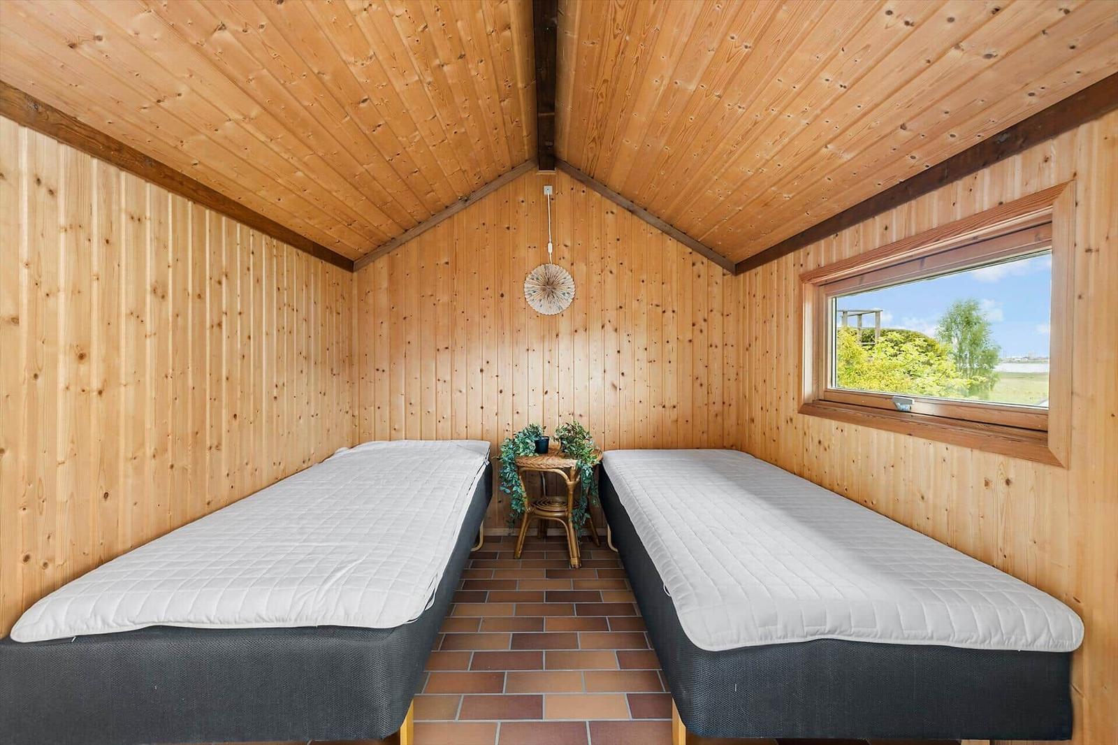 Zwei Matratzen in einem Holzhaus mit Fenster und kleinem Tisch.